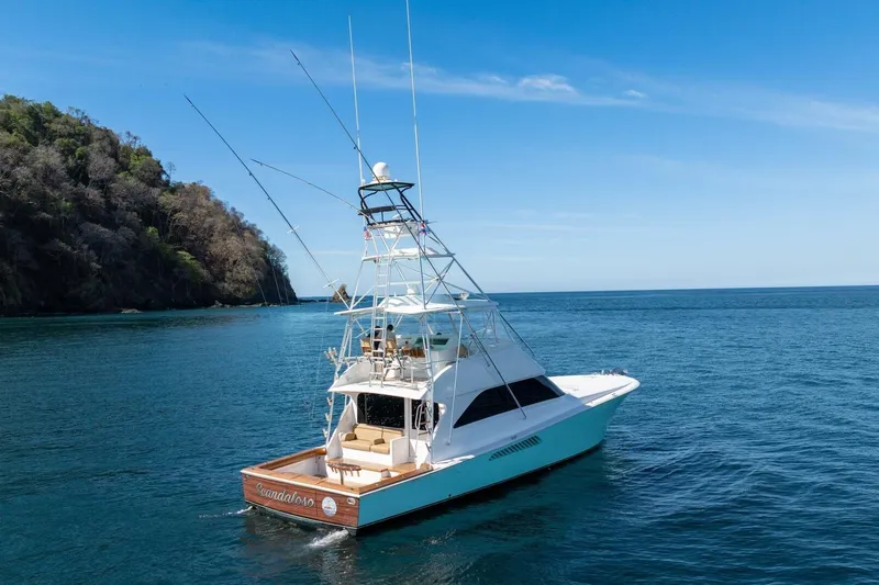 Scandaloso Yacht Photos Pics 2006 Viking 56 yacht cruising near a lush coastline under a clear blue sky.