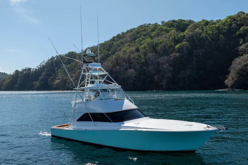 Scandaloso Yacht Photos Pics 2006 Viking 56 yacht on serene water with lush green hills in the background.