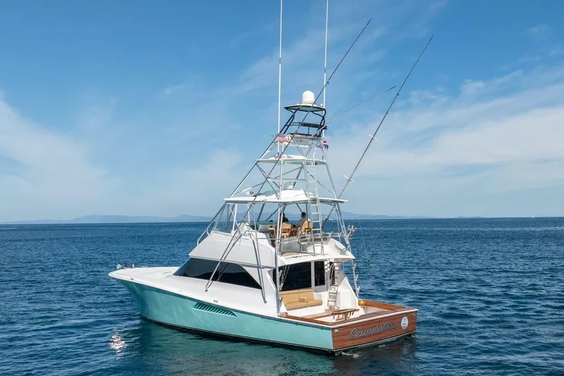 Scandaloso Yacht Photos Pics 2006 Viking 56 yacht on open sea, clear sky, fishing rods visible.