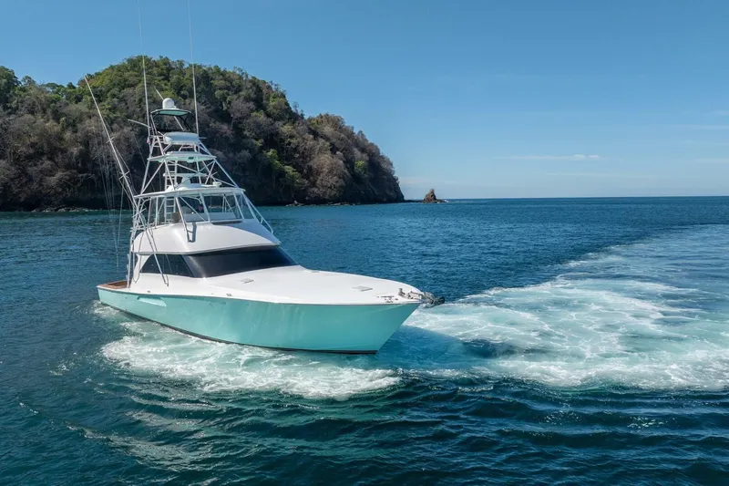 Scandaloso Yacht Photos Pics 2006 Viking 56 yacht cruising in clear blue waters near a forested island.