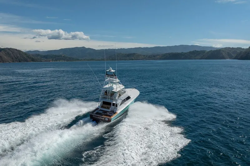 Scandaloso Yacht Photos Pics 2006 Viking 56 yacht cruising on open water with scenic mountain backdrop.