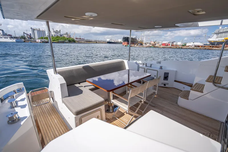  Yacht Photos Pics Luxurious 2019 Azimut 66 yacht deck with seating and table, overlooking a bustling harbor.
