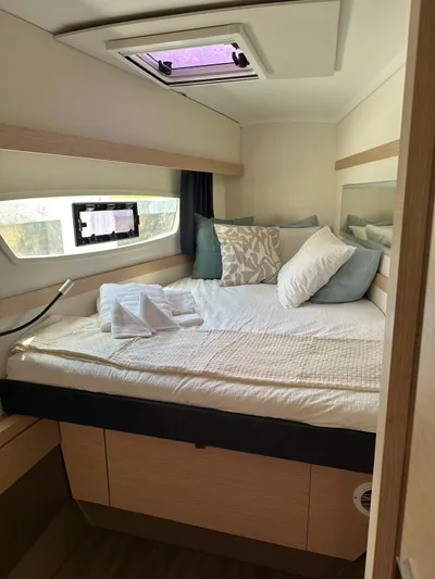 Vahevala Yacht Photos Pics Cozy cabin interior of 2019 Fountaine Pajot Lucia 40 catamaran with bed and porthole.