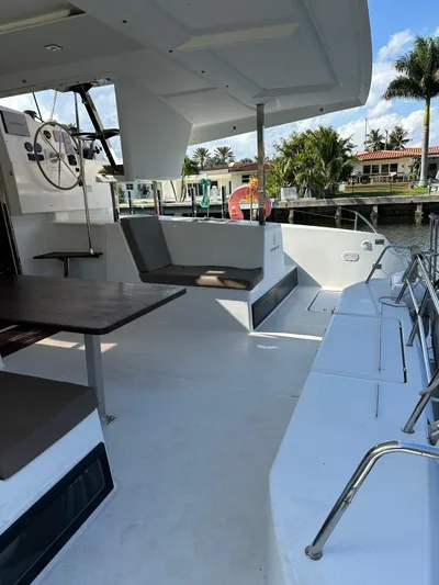 Vahevala Yacht Photos Pics 2019 Fountaine Pajot Lucia 40 catamaran with spacious outdoor seating and helm, docked by palm trees.