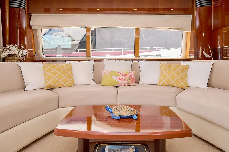  Yacht Photos Pics Luxurious yacht interior with beige seating, colorful cushions, and a polished wooden table.