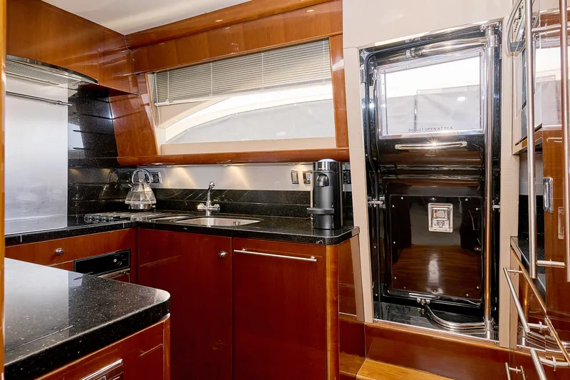  Yacht Photos Pics Luxurious yacht kitchen with wood cabinetry, modern appliances, and sleek black countertops, Princess 23M 2009.