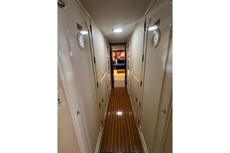 Long Tail Yacht Photos Pics Narrow hallway inside 1985 Hatteras 58 Motor Yacht with wooden flooring and white doors.