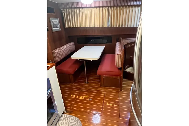 Long Tail Yacht Photos Pics 1985 Hatteras 58 Motor Yacht interior with dining booth and wooden flooring.