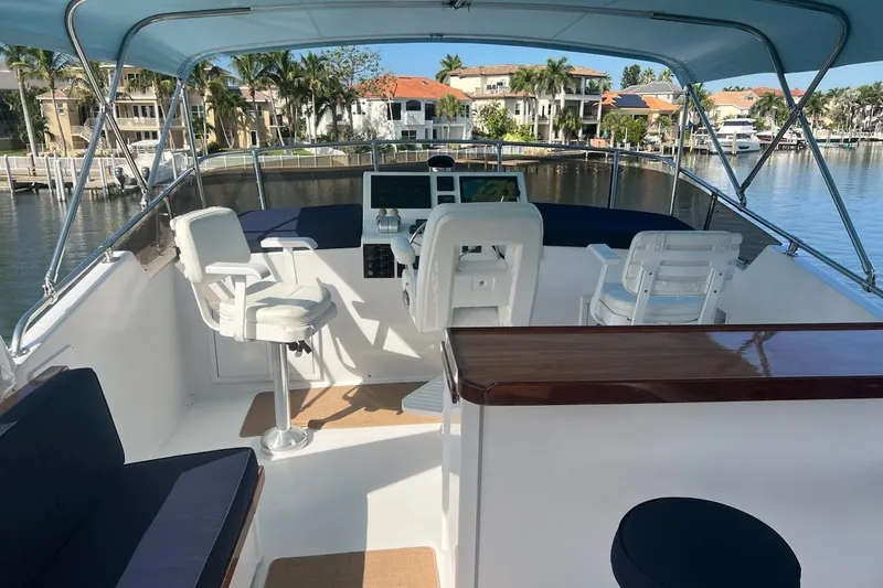 Long Tail Yacht Photos Pics 1985 Hatteras 58 Motor Yacht helm with seating, overlooking waterfront homes and palm trees.