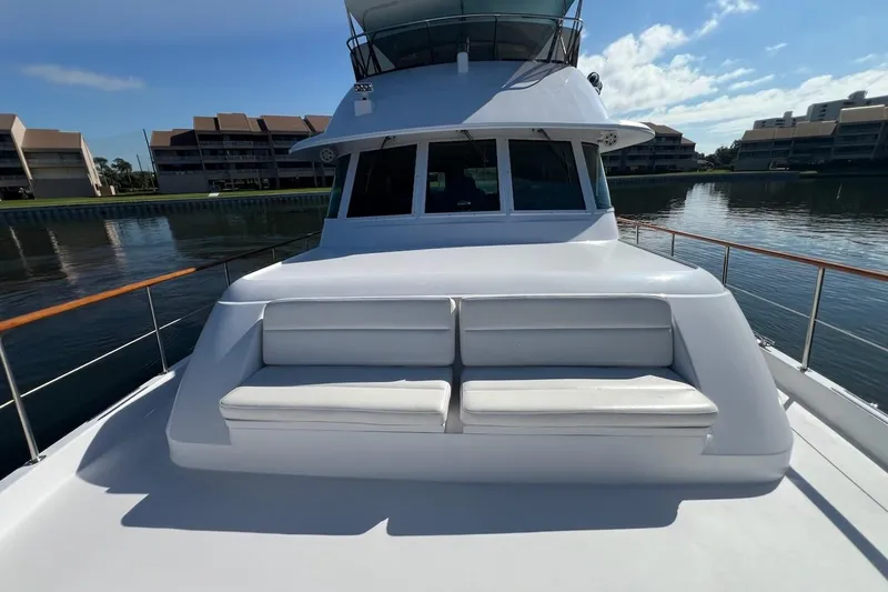 Long Tail Yacht Photos Pics 1985 Hatteras 58 Motor Yacht with white seating on deck, docked near waterfront buildings.
