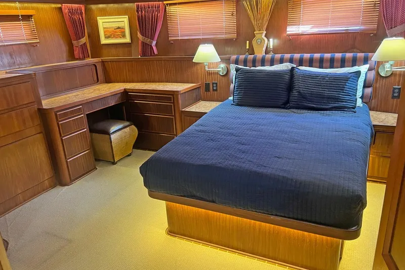 Long Tail Yacht Photos Pics Luxurious bedroom interior of 1985 Hatteras 58 Motor Yacht with wood furnishings and cozy lighting.