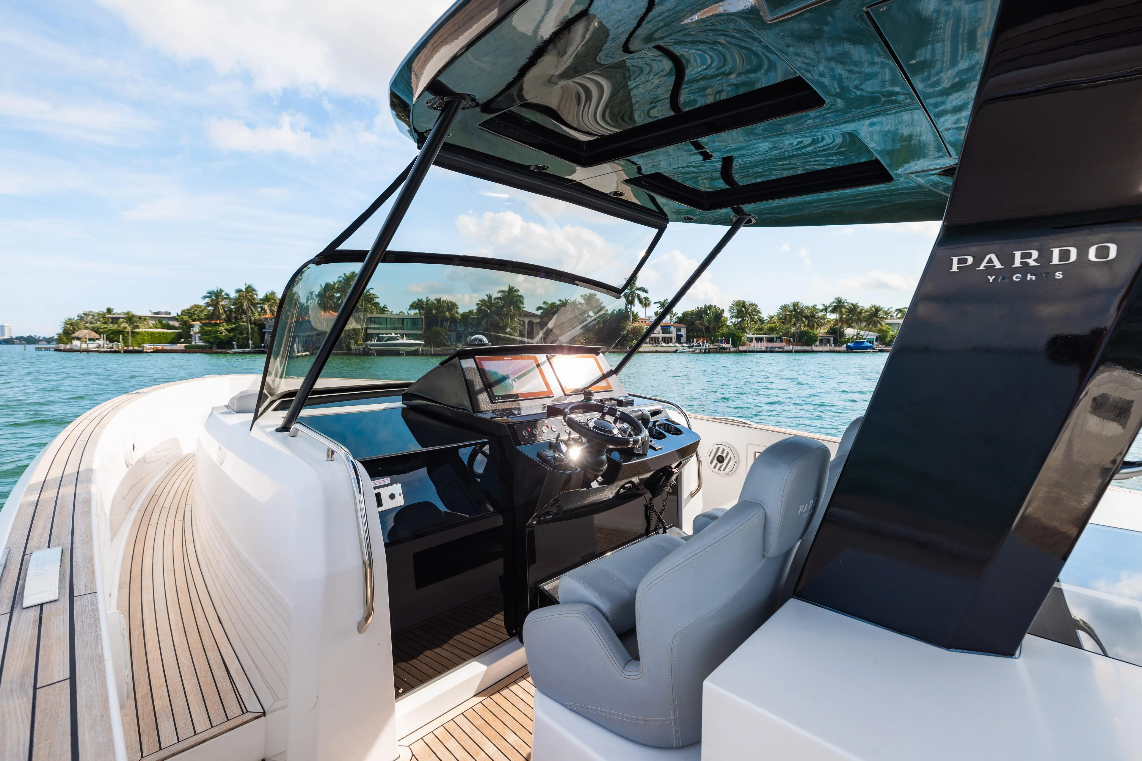 The Wolf Yacht Photos Pics 2021 Pardo Yachts 38 cockpit with modern controls, overlooking serene waterfront scenery.