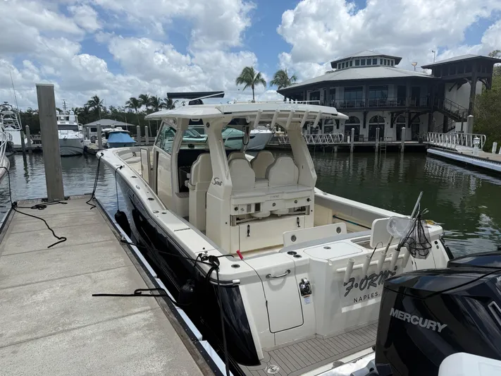  Yacht Photos Pics 2022 Scout 425 LXF boat docked at marina with Mercury engine, under cloudy sky.