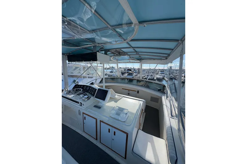 Sea Legs Yacht Photos Pics 1987 Bertram 46.6 yacht cockpit with helm, marina view, and blue canopy.