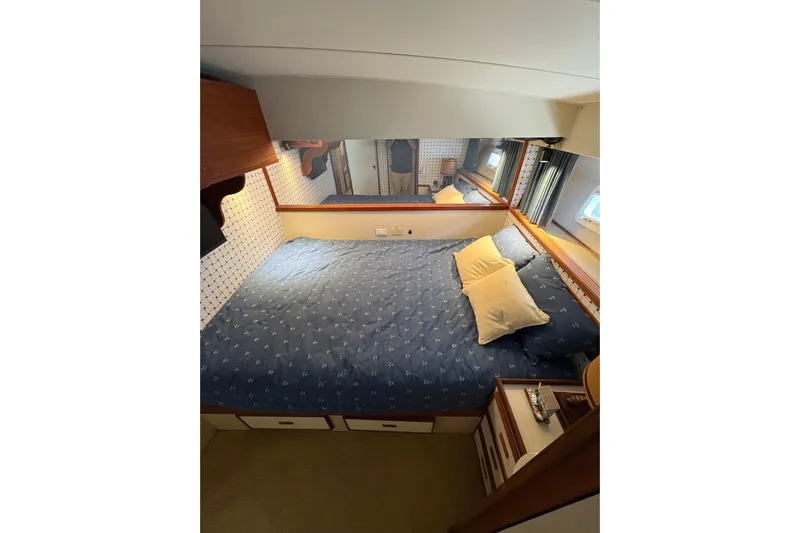 Sea Legs Yacht Photos Pics Cozy bedroom in 1987 Bertram 46.6 yacht with blue bedding and wooden accents.