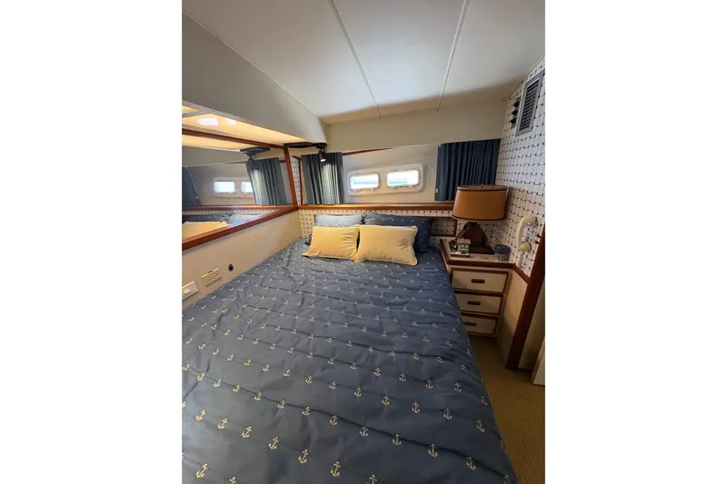 Sea Legs Yacht Photos Pics Cozy bedroom in 1987 Bertram 46.6 yacht with nautical-themed bedding and porthole windows.