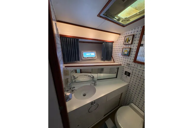 Sea Legs Yacht Photos Pics Bathroom interior of 1987 Bertram 46.6 yacht with sink, mirror, and nautical decor.
