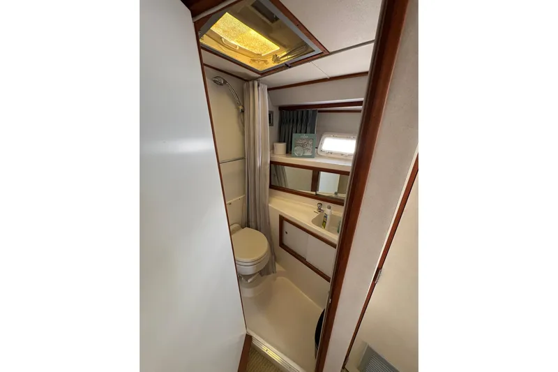 Sea Legs Yacht Photos Pics 1987 Bertram 46.6 yacht bathroom with shower, toilet, and sink, featuring wood accents.