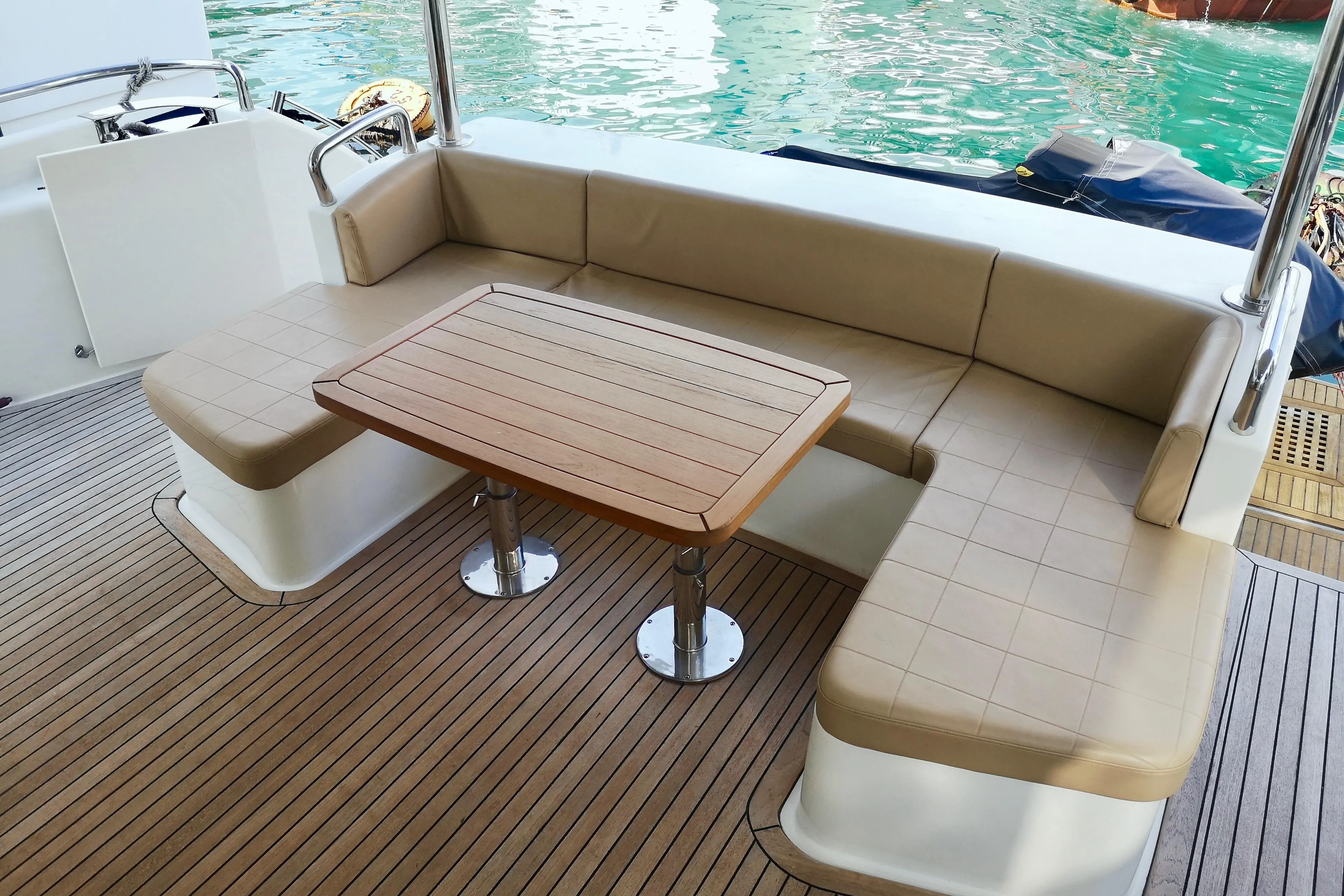 Luxurious seating area on a 2012 Ruby 65s yacht with wooden table and cushioned benches.