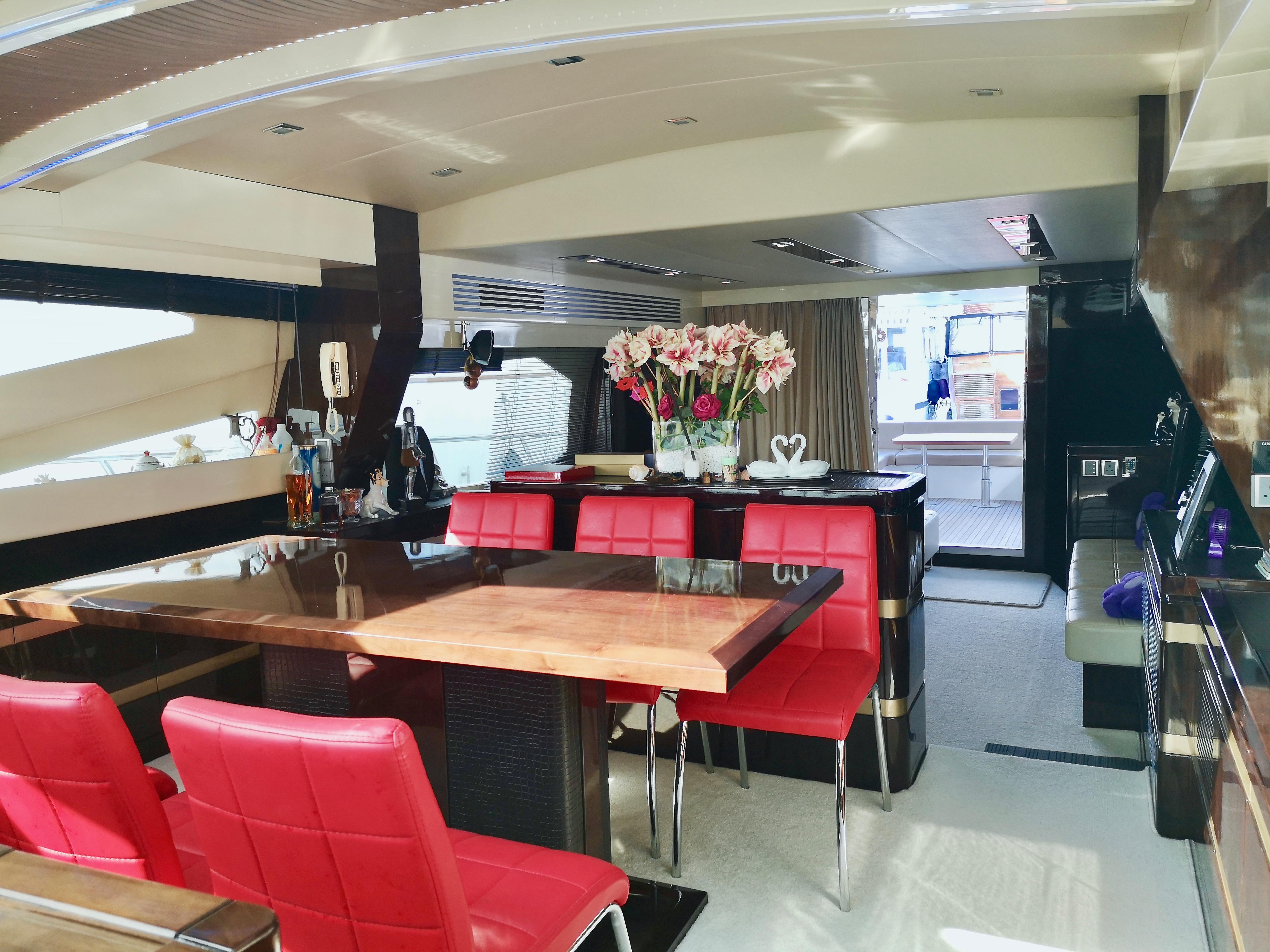 Luxurious Ruby 65s yacht interior with red chairs, wooden table, and elegant decor, 2012 model.