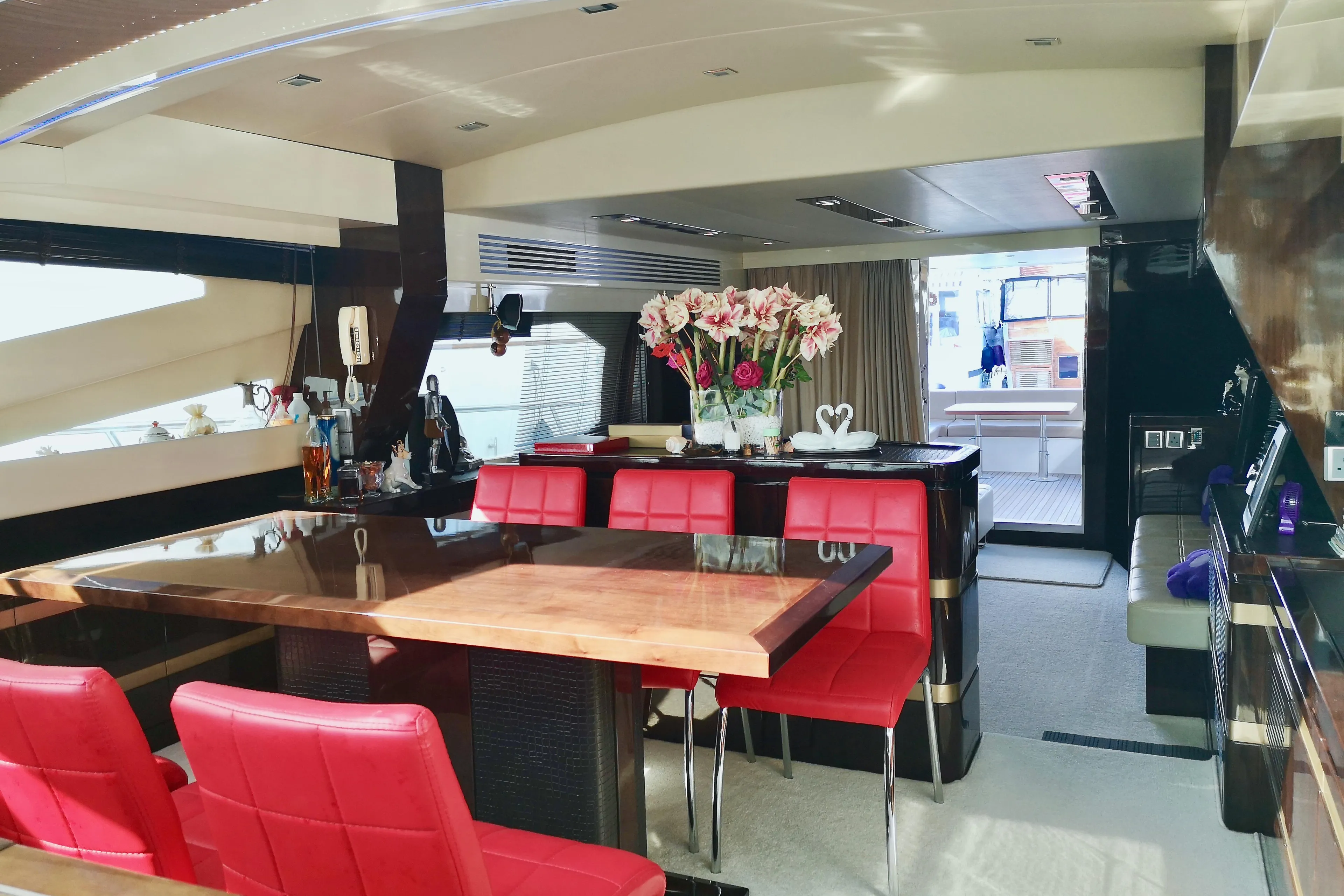 Luxurious Ruby 65s yacht interior with red chairs, wooden table, and elegant decor, 2012 model.