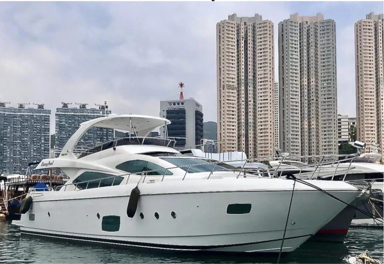 Luxurious 2012 Ruby 65s yacht docked in urban marina with skyscrapers in background.