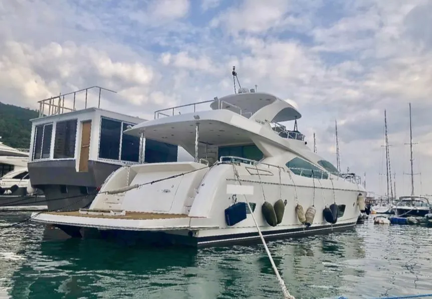 Luxurious 2012 Ruby 65s yacht docked in a marina under a cloudy sky.