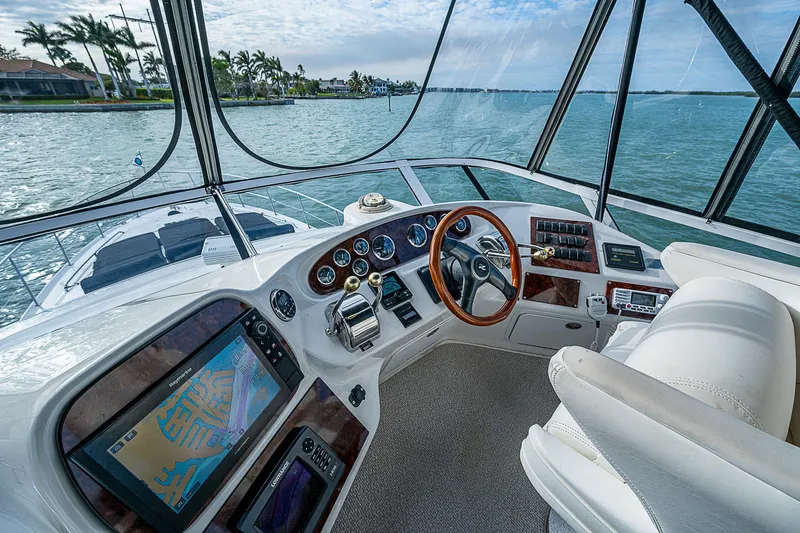 Feliz Dream Yacht Photos Pics 2001 Sea Ray 400 Sedan Bridge helm with navigation system, overlooking serene waters.