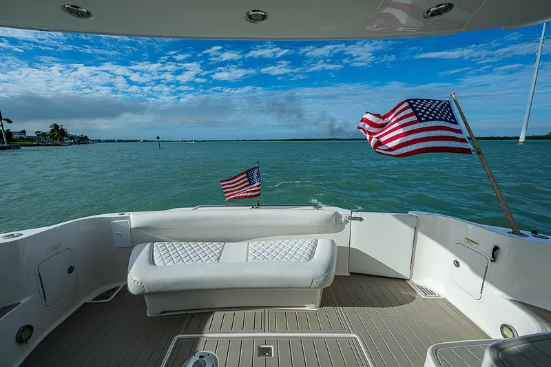 Feliz Dream Yacht Photos Pics 2001 Sea Ray 400 Sedan Bridge yacht deck with American flags, overlooking serene waters.