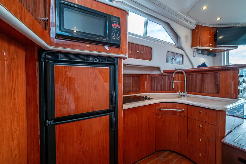 Feliz Dream Yacht Photos Pics Interior of 2001 Sea Ray 400 Sedan Bridge yacht kitchen with wood cabinetry and appliances.