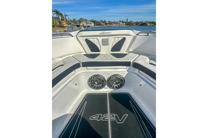  Yacht Photos Pics 2024 MTI V42 boat interior with sleek seating and dual speakers, docked by a scenic waterfront.