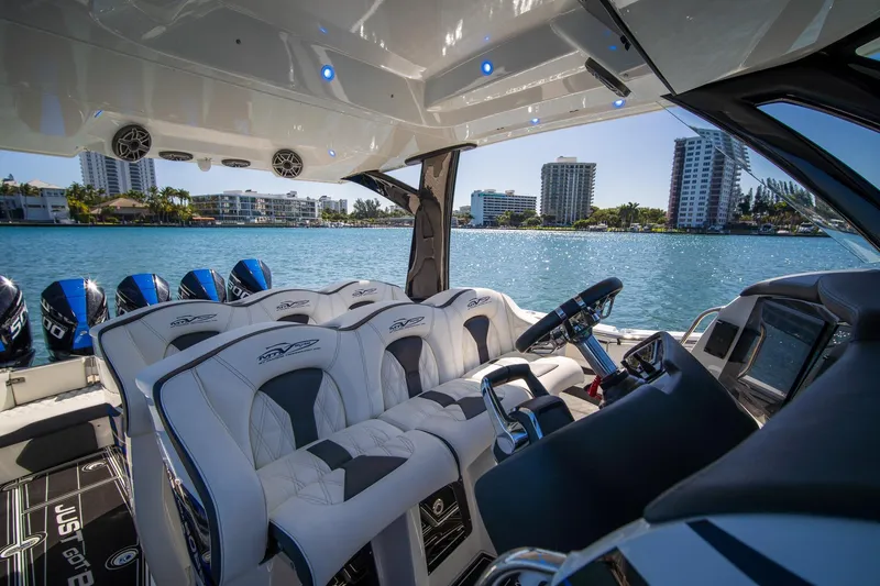  Yacht Photos Pics Luxurious 2024 MTI V42 boat interior with plush seating and modern controls on a sunny waterfront.