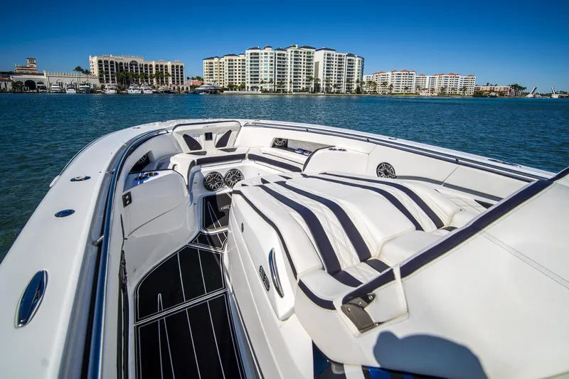  Yacht Photos Pics Luxurious 2024 MTI V42 boat interior with striped seating, docked near waterfront buildings.