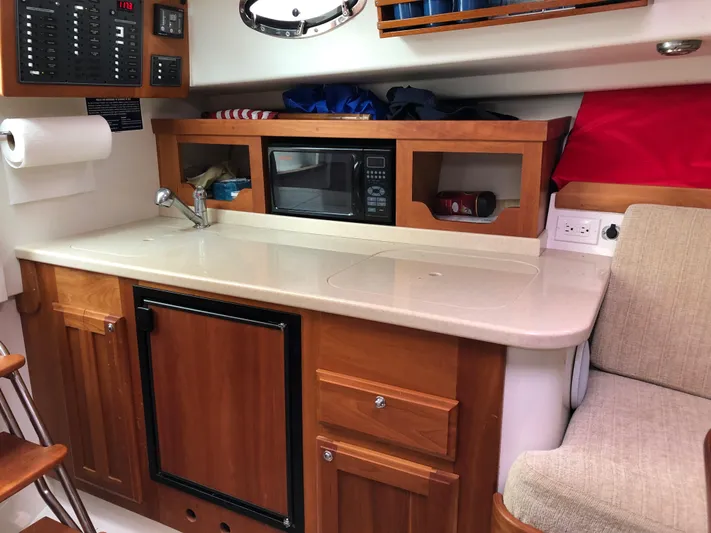 Act III Yacht Photos Pics 2008 Back Cove 29 boat interior with kitchenette, featuring sink, microwave, and wooden cabinetry.