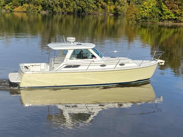 Act III Yacht Photos Pics 2008 Back Cove 29 boat cruising on calm water with lush green trees in the background.