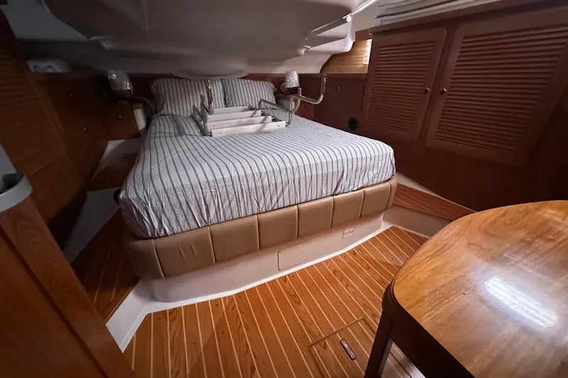 True North Yacht Photos Pics Cozy cabin interior of 2003 Catalina 470 sailboat with striped bedding and wooden furnishings.