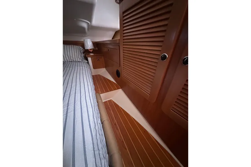 True North Yacht Photos Pics Interior of 2003 Catalina 470 yacht with wooden cabinetry and striped bedding.