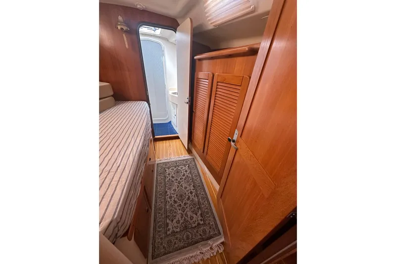 True North Yacht Photos Pics Cozy cabin interior of 2003 Catalina 470 yacht with wooden finishes and striped bedding.