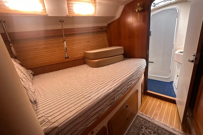 True North Yacht Photos Pics Cozy cabin interior of 2003 Catalina 470 sailboat with striped bedding and wooden accents.