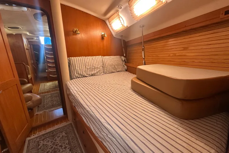 True North Yacht Photos Pics Cozy cabin interior of 2003 Catalina 470 sailboat with striped bedding and wooden accents.