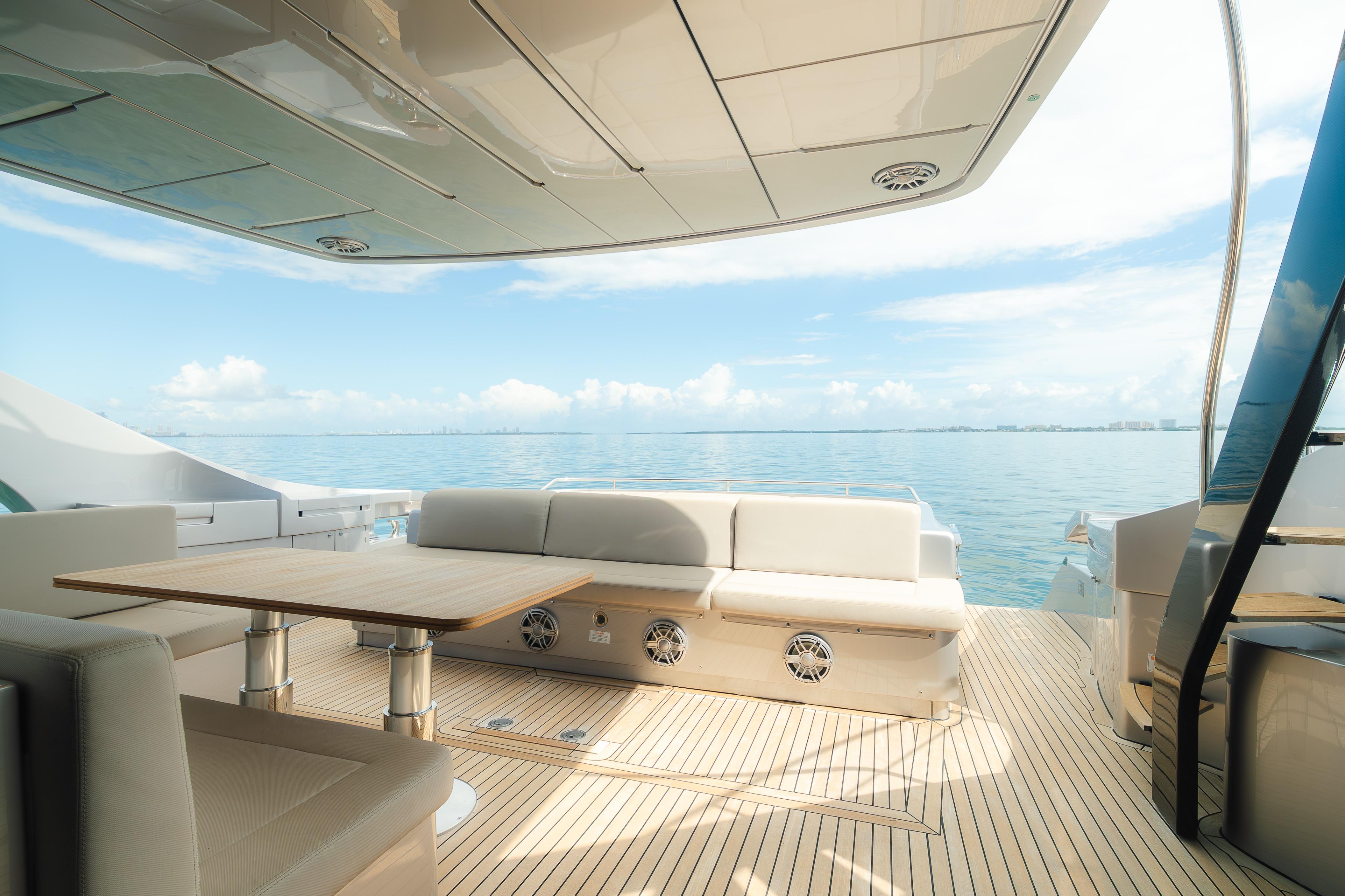 Luxurious 2021 Pershing 8X yacht deck with seating, table, and ocean view.