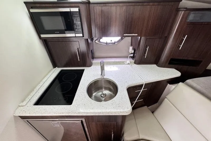  Yacht Photos Pics 2018 Regal 35 Sport Coupe kitchen with microwave, sink, and stovetop in compact design.