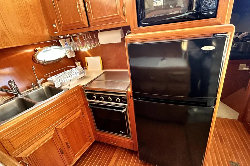 Chrysalis Yacht Photos Pics 1989 Ocean Alexander 44 CPMY yacht kitchen with wood cabinetry, black appliances, and double sink.