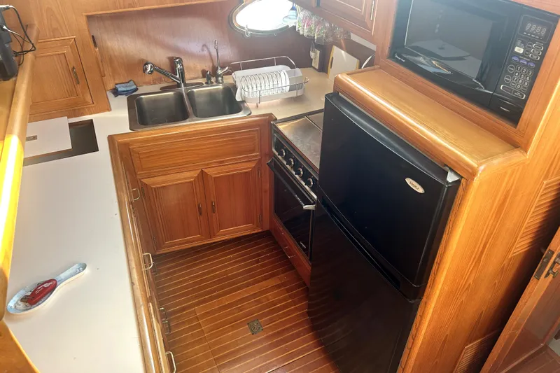 Chrysalis Yacht Photos Pics 1989 Ocean Alexander 44 CPMY yacht kitchen with wood cabinetry, sink, stove, and microwave.