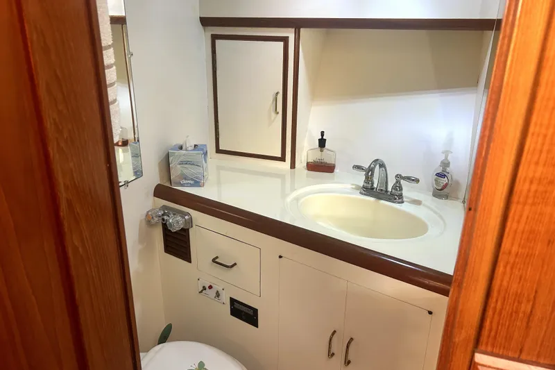 Chrysalis Yacht Photos Pics 1989 Ocean Alexander 44 CPMY yacht bathroom with sink, mirror, and wooden cabinetry.