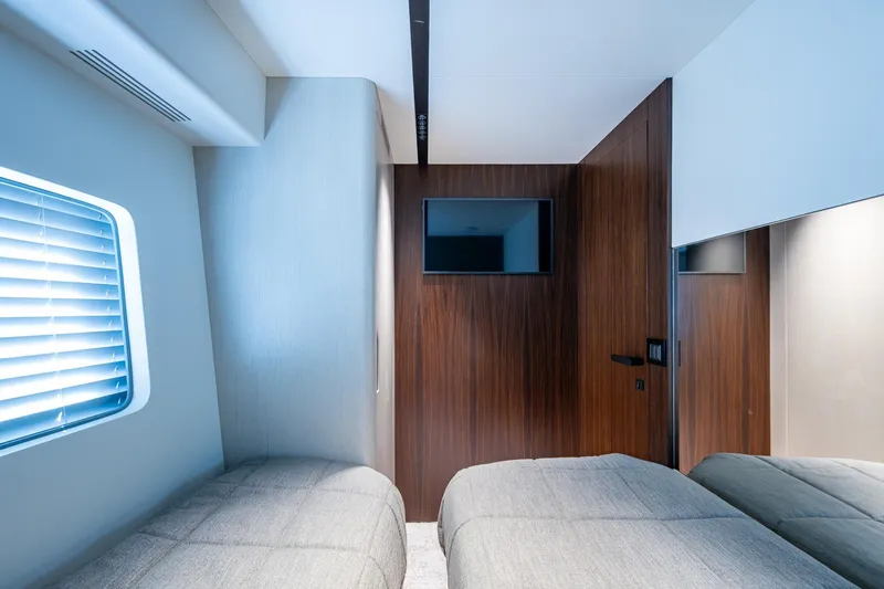 Alamar Yacht Photos Pics 2023 Astondoa AS5 yacht cabin with twin beds, wooden accents, and a wall-mounted TV.