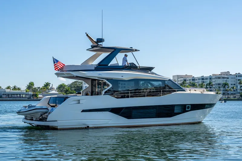 Alamar Yacht Photos Pics 2023 Astondoa AS5 yacht cruising on a sunny day near waterfront buildings.