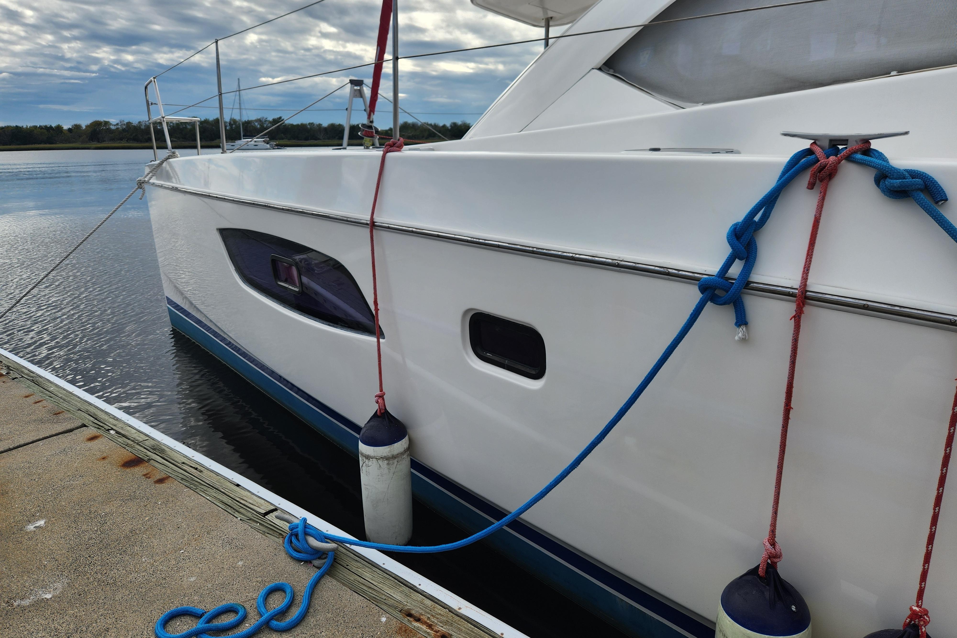 Leopard 44 catamaran docked, secured with ropes, featuring sleek design and calm waters.