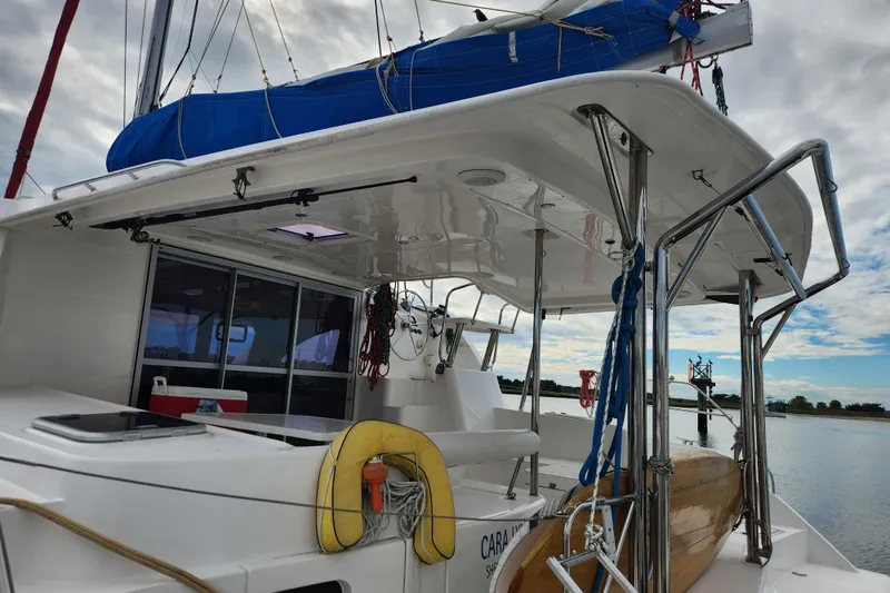 Cara Lynn Yacht Photos Pics 2015 Leopard 44 catamaran with blue sail cover, docked on a calm waterway.