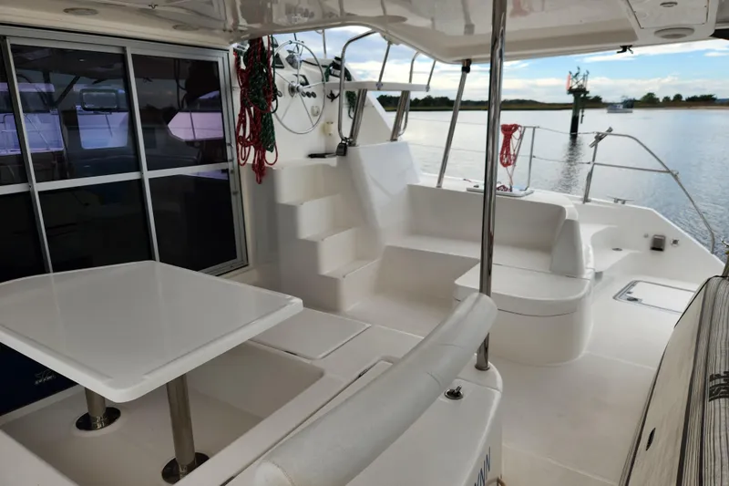 Cara Lynn Yacht Photos Pics Spacious deck of 2015 Leopard 44 catamaran with seating and table, overlooking calm waters.